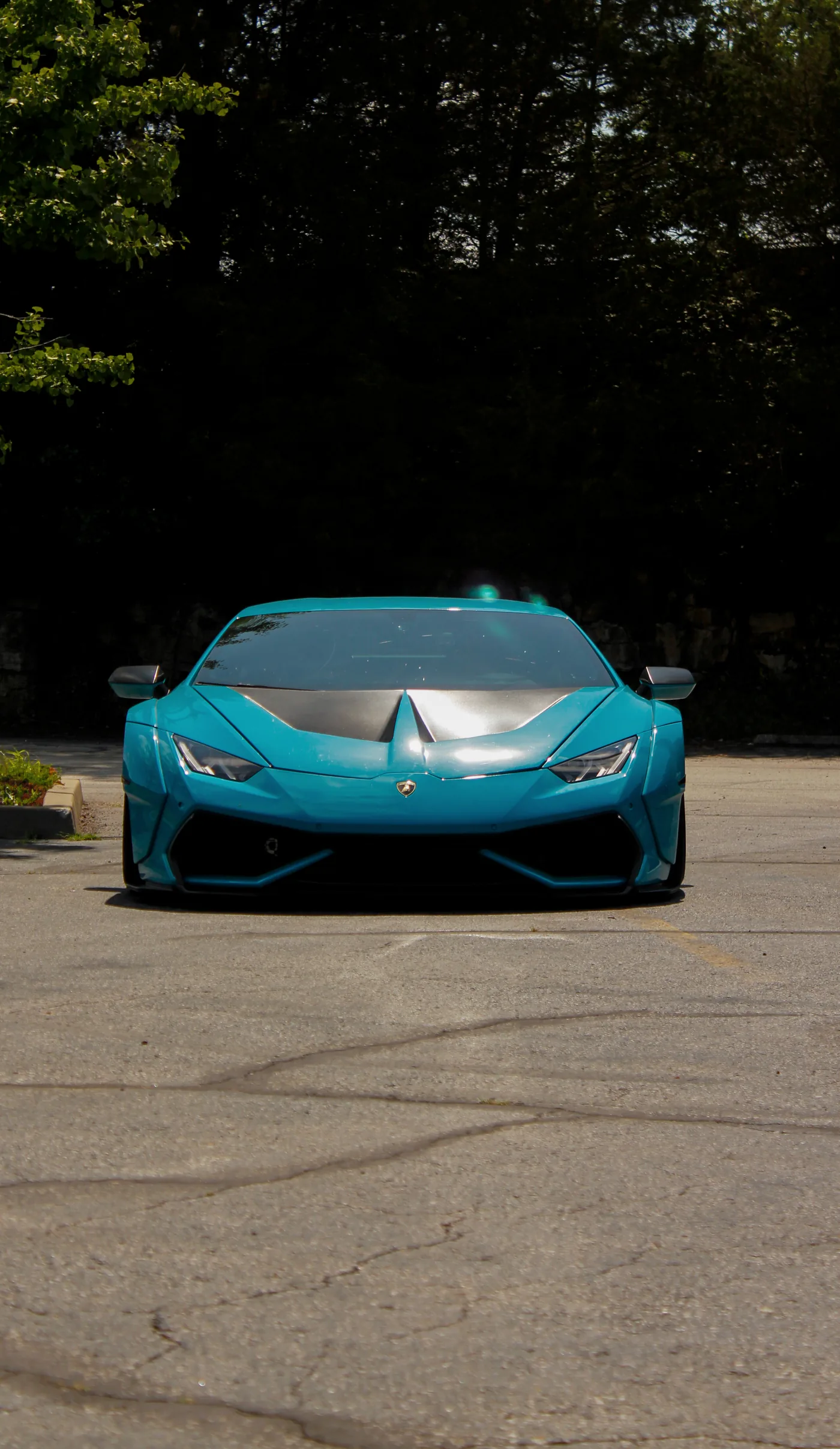 Teal Lamborghini Huracan shot head-on against dark trees